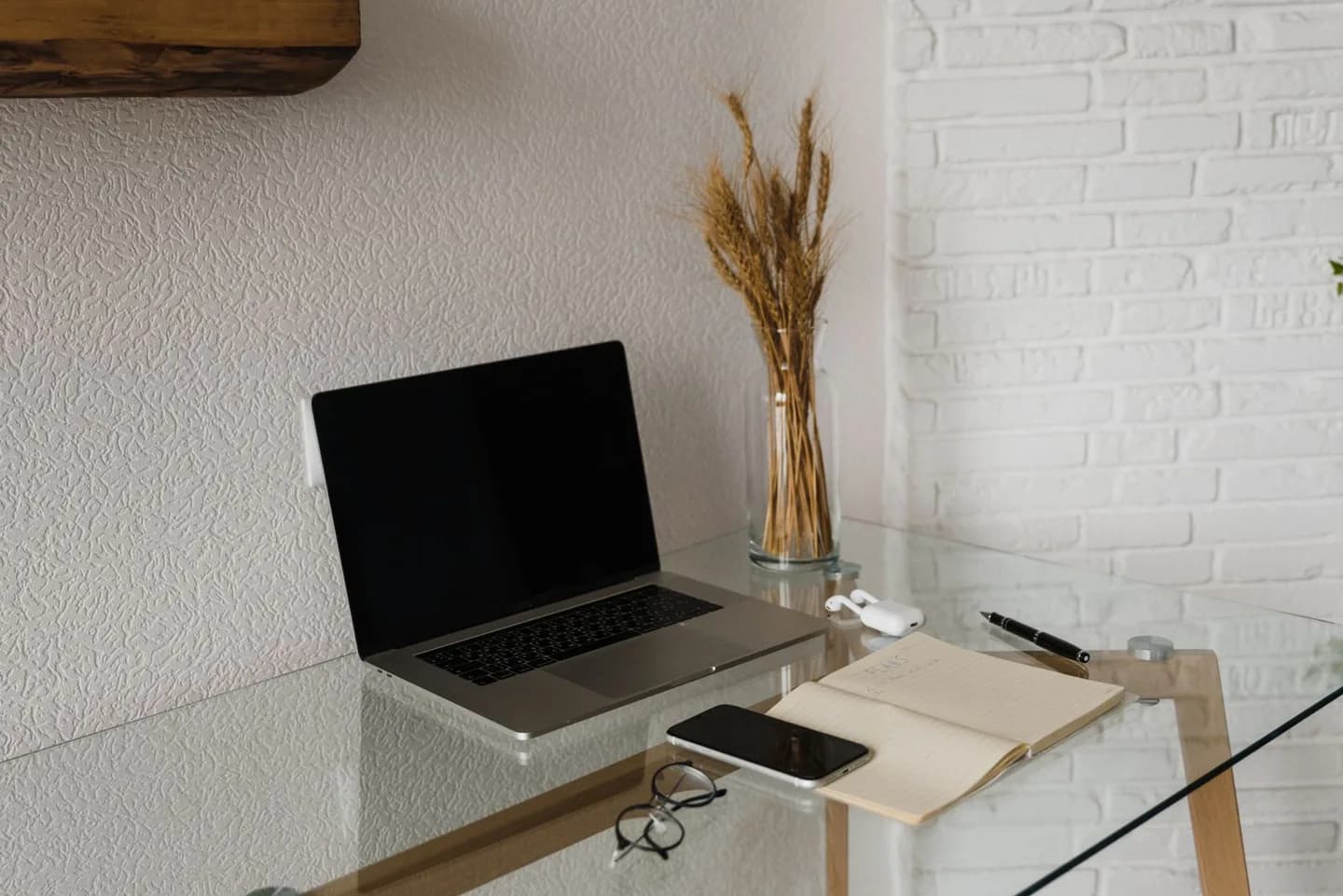 Laptop, smartphone and notebook on a glass work desk