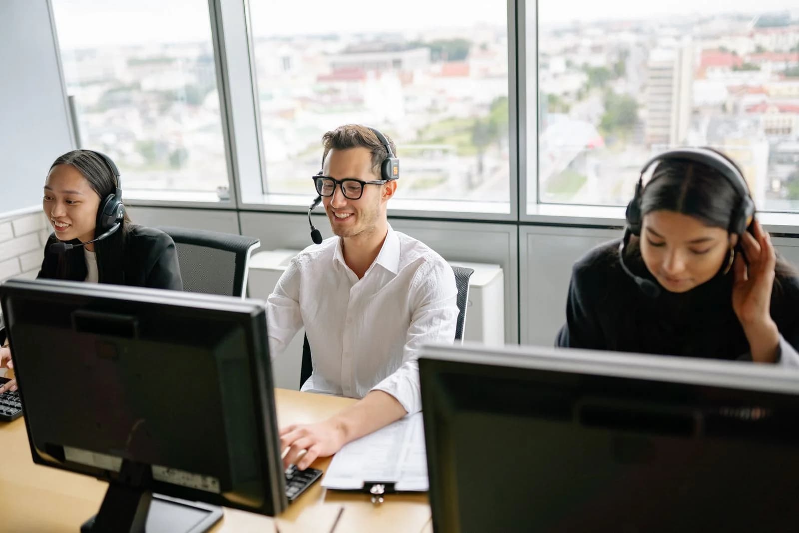 Helpdesk team wearing headsets and handling support calls at desktop computers